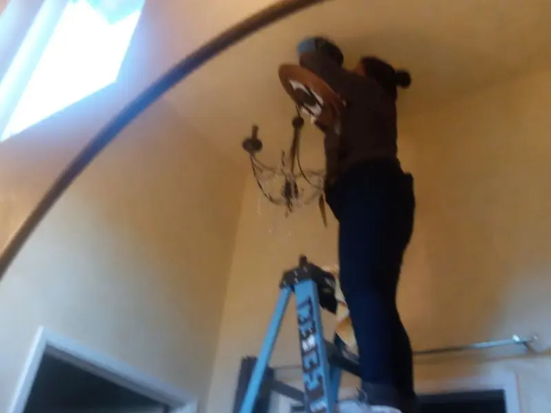 Electrician installing a chandelier in a Coconut Creek residence